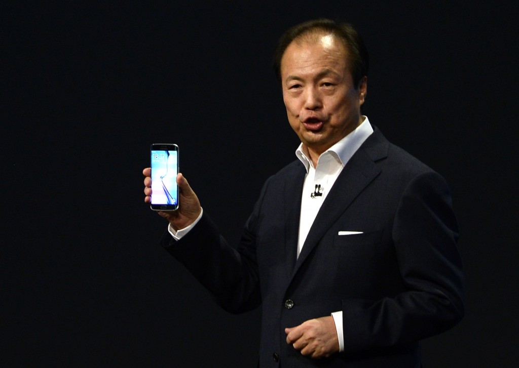 JK Shin, CEO of Samsung's mobile division, shows the new Galaxy S6 and S6 Edge, during a Samsung Galaxy Unpacked 2015 event on the eve of this weeks Mobile World Congress wireless show, in Barcelona, Spain, Sunday, March 1, 2015. Samsung unveiled a stylish new flagship phone that ditches its signature plastic design for metal and glass. The South Korean phone manufacturer also unveiled a premium model with a display that curves around the left and right edges so that information can be quickly glanced at on the side. (AP Photo/Manu Fernandez)
