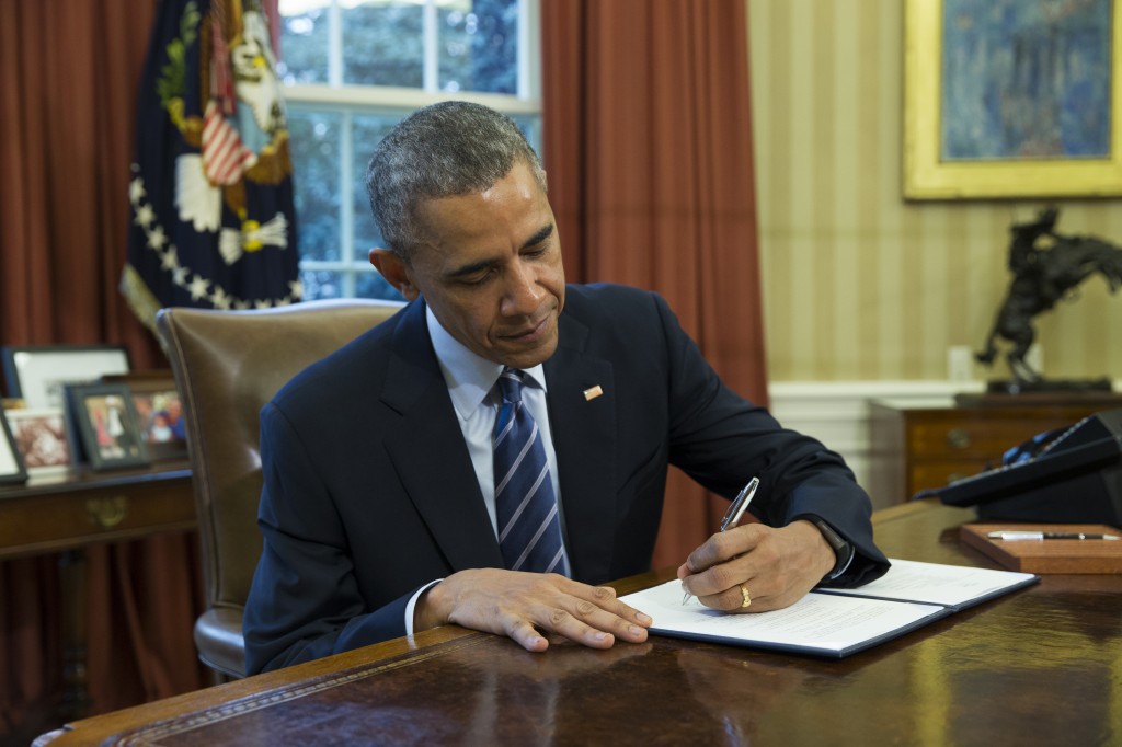 President Barack Obama signs a presidential memorandum aiming to clamp down on the private companies that service federal student debt, Tuesday, March 10, 2015, in the Oval Office of the White House in Washington. (AP Photo/ Evan Vucci)