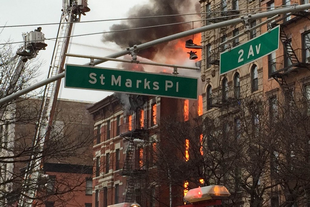 New York City firefighters work the scene of a large fire and a partial building collapse in the East Village neighborhood of New York on Thursday, March 26, 2015. Orange flames and black smoke are billowing from the facade and roof of the building near several New York University buildings.  (AP Photo/Suzanne Mitchell)