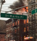 New York City firefighters work the scene of a large fire and a partial building collapse in the East Village neighborhood of New York on Thursday, March 26, 2015. Orange flames and black smoke are billowing from the facade and roof of the building near several New York University buildings.  (AP Photo/Suzanne Mitchell)
