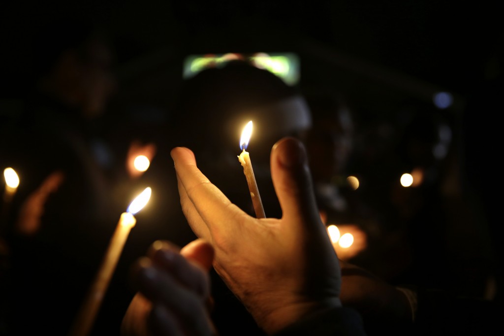 People take part in a candlelight vigil Thursday, March 12, 2015, in Ferguson, Mo. Two police officers were shot early Thursday morning in front of the Ferguson Police Department during a protest following the resignation of the city's police chief in the wake of a U.S. Justice Department report. (AP Photo/Jeff Roberson)