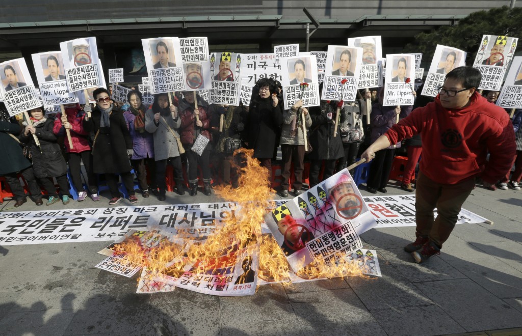 A South Korean conservative activist burns a North Korean flag, portraits of North Korea leader Kim Jon Un and Kim Ki-jong, the suspect of slashing U.S. Ambassador to South Korea Mark Lippert, during a rally demanding speedy recovery of Lippert near the U.S. embassy in Seoul, South Korea, Friday, March 6, 2015. A knife attack Thursday that injured Lippert is the latest act of political violence in a deeply divided country where some protesters portray their causes as matters of life and death. The letters at a banner read " A rally demanding speedy recovery of U.S. Ambassador to South Korea Mark Lippert  " (AP Photo/Ahn Young-joon)