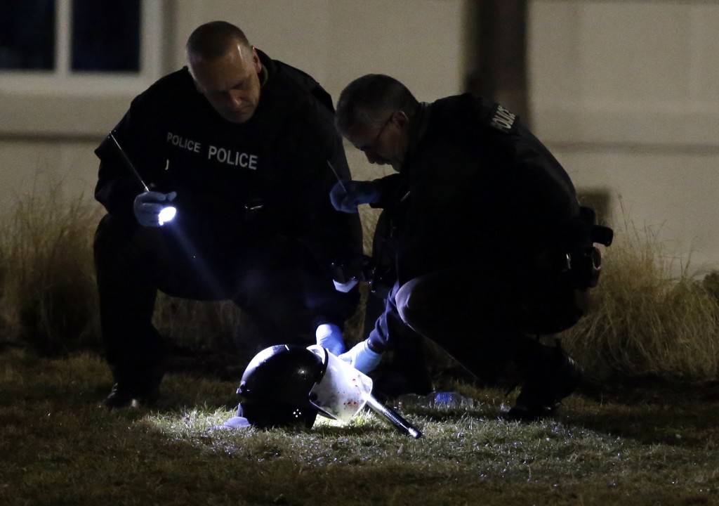 Police shine a light on a helmet as they investigate the scene where two police officers were shot outside the Ferguson Police Department Thursday, March 12, 2015, in Ferguson, Mo. (AP Photo/Jeff Roberson)