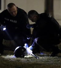 Police shine a light on a helmet as they investigate the scene where two police officers were shot outside the Ferguson Police Department Thursday, March 12, 2015, in Ferguson, Mo. (AP Photo/Jeff Roberson)