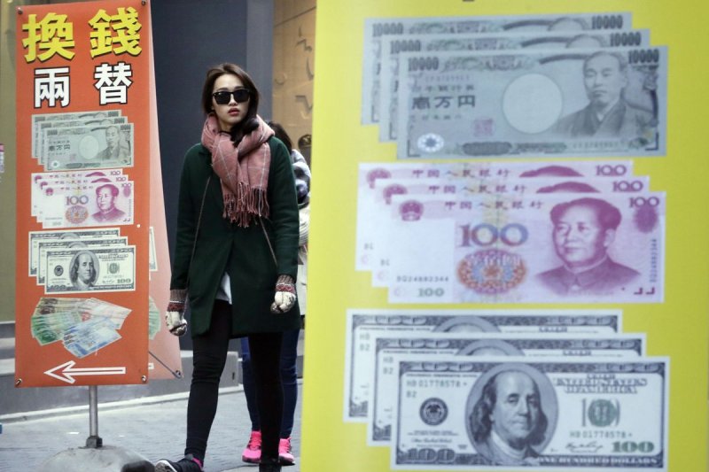 A woman passes by signs of foreign exchange in Seoul, South Korea, Thursday, March 12, 2015. South Korea unexpectedly lowered its benchmark interest rate Thursday to a record low of 1.75 percent, joining central banks from Europe to India in efforts to revitalize sluggish economic growth.(AP Photo/Ahn Young-joon)