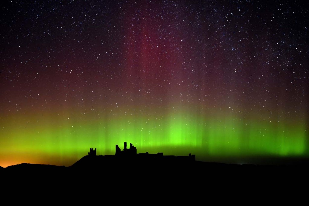 The aurora borealis, or the northern lights as they are commonly known are photographed, over Dunstanburgh Castle, in Northumberland, England (AP Photo/PA, Owen Humphreys)