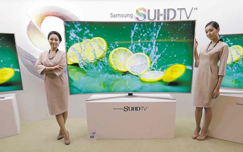 Models pose with a Samsung Electronics Co.' SUHD 4K smart TV during a press conference in Seoul, South Korea. (AP Photo/Ahn Young-joon)