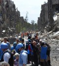 FILE - This picture taken on Thursday, April. 24, 2014 and provided by the United Nations Relief and Works Agency for Palestine Refugees in the Near East (UNRWA), U.N relief workers with blue helmets and vests stand next of residents of the besieged Palestinian camp of Yarmouk, right, who stand in line to receive aid food distributed by UNRWA, on the southern edge of the Syrian capital Damascus, Syria. On wednesday, April. 1, 2015 Islamic State militants infiltrated the Palestinian refugee camp of Yarmouk in the Syrian capital marking the deepest foray yet by the extremist group into Damascus, seat of President Bashar Assads power, Syrian opposition activists and Palestinian officials said. (AP Photo/UNRWA, File )