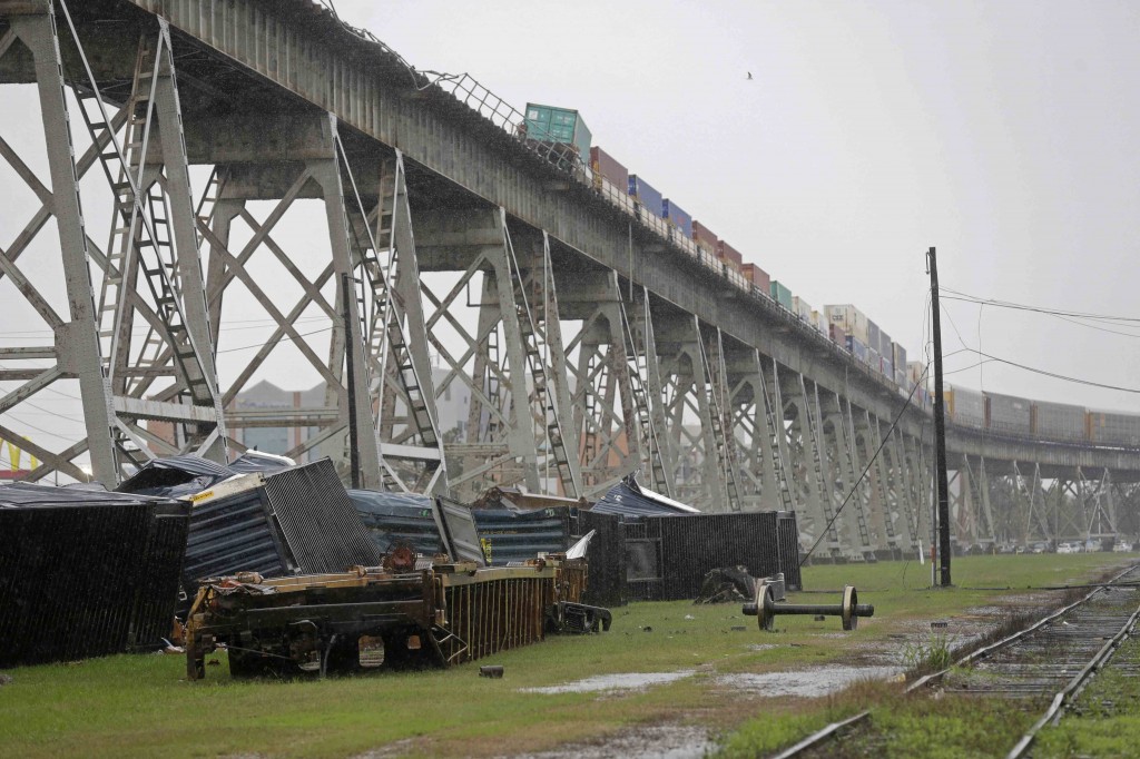 Train cars are crashed beneath the Huey P. Long Bridge, which crosses over the Mississippi River, after they toppled off the bridge from high winds in Jefferson Parish, La., just outside New Orleans, Monday, April 27, 2015. More than 200,000 homes and businesses lost power and at least four cars carrying freight containers were blown off the approach to the Huey P. Long Bridge outside New Orleans as a line of severe thunderstorms moved across southeast Louisiana. None of the freight containers held hazardous cargo, and nobody was injured,  (AP Photo/Gerald Herbert)