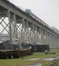 Train cars are crashed beneath the Huey P. Long Bridge, which crosses over the Mississippi River, after they toppled off the bridge from high winds in Jefferson Parish, La., just outside New Orleans, Monday, April 27, 2015. More than 200,000 homes and businesses lost power and at least four cars carrying freight containers were blown off the approach to the Huey P. Long Bridge outside New Orleans as a line of severe thunderstorms moved across southeast Louisiana. None of the freight containers held hazardous cargo, and nobody was injured,  (AP Photo/Gerald Herbert)