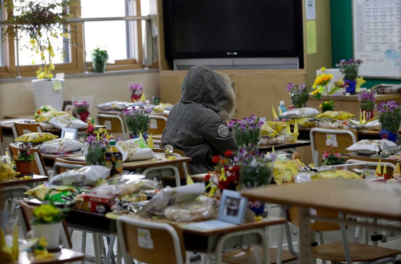 In this picture taken on Wednesday, April 8, 2015, an alumna sits in a victim's chair inside a classroom at Danwon High School in Ansan, south of Seoul, South Korea. One year ago the ferry Sewol carrying 325 second-year students on a field trip to a southern island sank; only 75 survived. Their classrooms in this city about an hour south of Seoul have barely changed from the day they left for the trip. (AP Photo/Lee Jin-man)