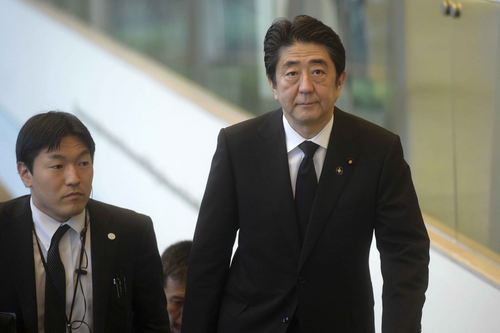 Japan's Prime Minister Shinzo Abe, right, arrives at the state funeral for the late Lee Kuan Yew, at the University Cultural Center,  Sunday, March 29, 2015 in Singapore.  During a week of national mourning that began Monday after Lee's death at age 91, some 450,000 people queued for hours for a glimpse of Lee's coffin at Parliament House. A million people visited tribute sites at community centers across the island and leaders and dignitaries from more than two dozen countries attended the state funeral. (AP Photo/Joseph Nair)