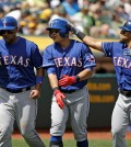 Texas Rangers' Shin-Soo Choo, center, of South Korea, is greeted by teammates Carlos Corporan, left, and Rougned Odor, right, after hitting a three run homer off Oakland Athletics starting pitcher Kendall Graveman in the fourth inning of their baseball game Thursday, April 9, 2015, in Oakland, Calif. (AP Photo/Eric Risberg)