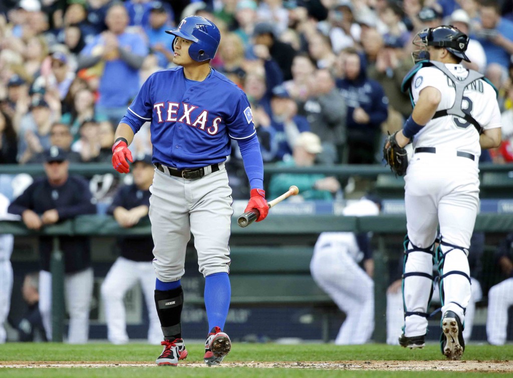Texas Rangers' Choo Shin-Soo, left, walks to the dugout after he struck out swinging against the Seattle Mariners in the first inning of a baseball game, Saturday, April 18, 2015, in Seattle. (AP Photo/Ted S. Warren)