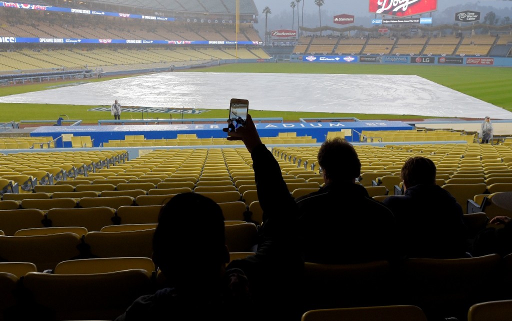 A fan takes a picture during a rain delay prior to a baseball game between the Los Angeles Dodgers and the San Diego Padres, Tuesday, April 7, 2015, in Los Angeles. (AP Photo/Mark J. Terrill)