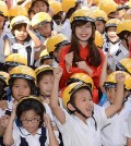 Students rejoice at Nguyen Viet Xuan Elementary School in Ho Chi Minh City on April 8, 2015, after receiving motorcycle helmets from South Korean retailer E-Mart. In Vietnam, many children are injured in motorcycle accidents as they do not wear helmets. E-Mart plans to give out 10,000 helmets a year. (pool photo) (Yonhap)