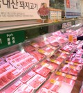 A shopper takes a look at pork at a retailer. (Korea Times file)