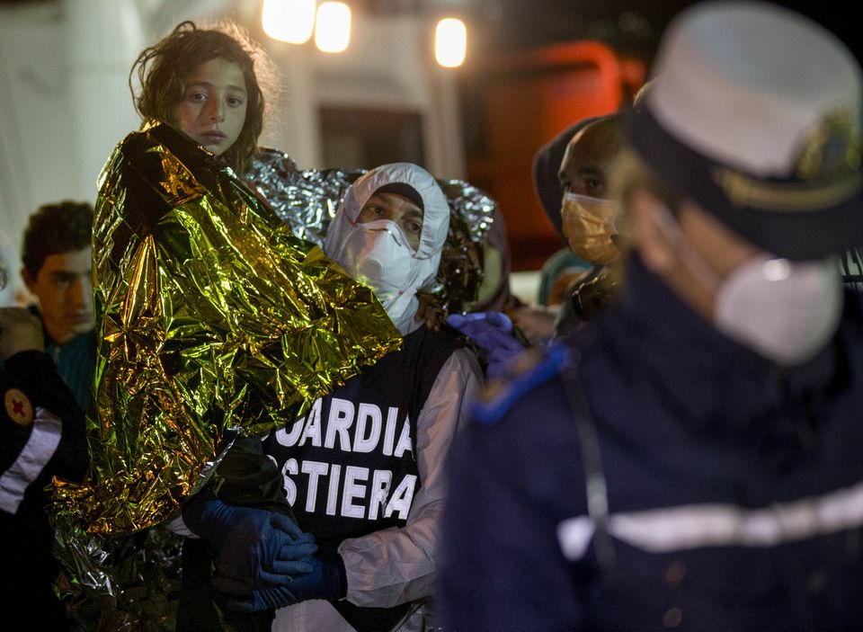 A migrant is helped disembark in the Sicilian harbor of Pozzallo, Italy, early Monday, April 20, 2015. About 100 migrants, including 28 children, were rescued on Sunday by a merchant vessel in the Sicilian Strait while they were trying to cross. Another smuggler's boat crammed with hundreds of people overturned off Libya's coast on Saturday as rescuers approached, causing what could be the Mediterranean's deadliest known migrant tragedy and intensifying pressure on the European Union Sunday to finally meet demands for decisive action. (AP Photo/Alessandra Tarantino)