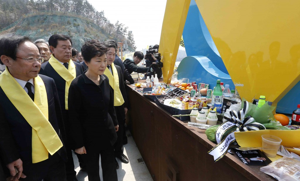 South Korean President Park Geun-hye, front right, looks at foods and beverages dedicated for the victims of the sunken ferry Sewol as she arrives to offer her condolences to the bereaved relatives of the victims at a port in Jindo, South Korea, Thursday, April 16, 2015. Tears and grief mixed with raw anger Thursday as black-clad relatives mourned the 300 people, mostly high school kids, killed one year ago when the ferry Sewol sank in cold waters off the southwestern South Korean coast. (Lee Jeong-ryong/Yonhap via AP) KOREA OUT