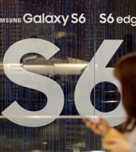 A woman walks by the advertisement of Samsung's Galaxy S6 smartphone outside its showroom in Seoul, South Korea, Wednesday, April 29, 2015. Samsung Electronics Co. said its first-quarter net income plunged 39 percent as consumers switched to bigger iPhones, squeezing its profit from the mobile business to less than half from a year earlier. (AP Photo/Lee Jin-man)