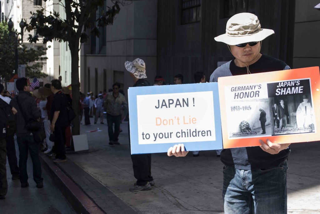 Alexander Feng, 34, holds two signs
