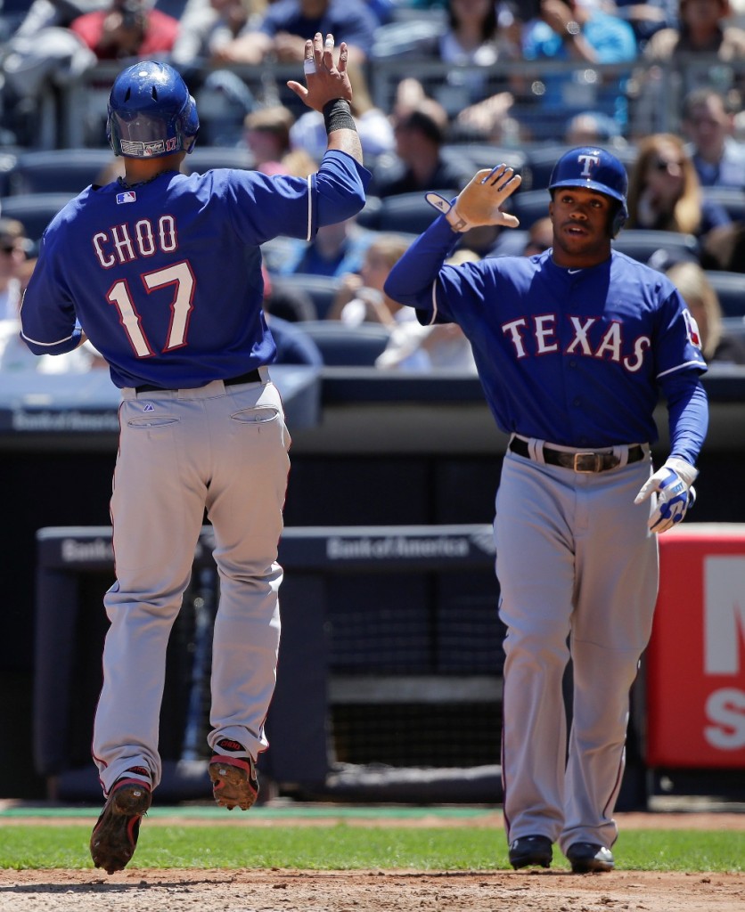 Texas Rangers' Shin-Soo Choo (17) is greeted by Delino DeShields (7) after both scored on a base hit by Rangers designated hitter Prince Fielder during the third inning of a baseball game against the New York Yankees, Saturday, May 23, 2015, in New York. (AP Photo/Julie Jacobson)