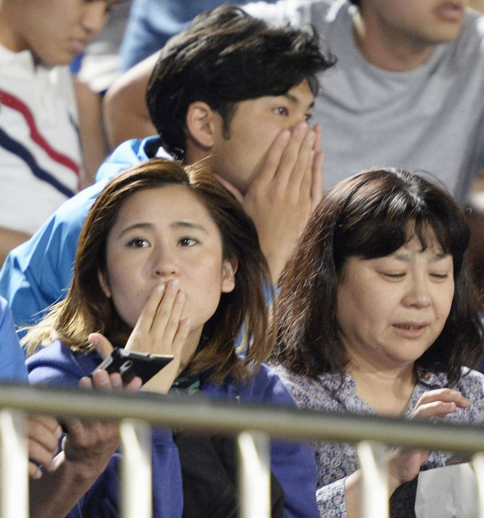 Japanese soccer fans react to a strong earthquake as they watch a J-League soccer match between the Shonan Bellmare and the Sanfrecce Hiroshima at BMW Stadium in Hiratsuka, southwest of Tokyo Saturday, May 30, 2015. A powerful and extremely deep earthquake struck a group of remote Japanese islands and shook Tokyo on Saturday, but officials said there was no danger of a tsunami, and no injuries or damage were immediately reported. (Munehide Someya/Kyodo News via AP)