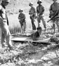 U.S. Marines cover wounded North Korean soldier as he hoists himself to stretcher in the Naktong River sector of the Korean front on August 23, 1950. The captive was flushed out of a nearby rice paddy, still clutching his automatic weapons. A search of his clothing disclosed an American watch, lighter and other items apparently taken from a dead U.S. soldier. (AP Photo/Max Desfor)