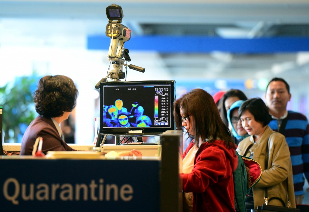 A quarantine official (left) checks people arriving at South Korea's Incheon International Airport for signs of fever. Now the epidemic has spread to China. (Newsis)  