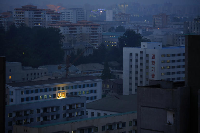 Portraits of the late North Korean leaders Kim Il Sung, left, and Kim Jong Il, right, glow on the facade of a building as dusk descends upon Pyongyang, North Korea, May 8, 2015. In Pyongyang, commercial advertisements are rarely seen in public, but portraits of the late leaders and propaganda slogans are a common sight on buildings and along the streets.