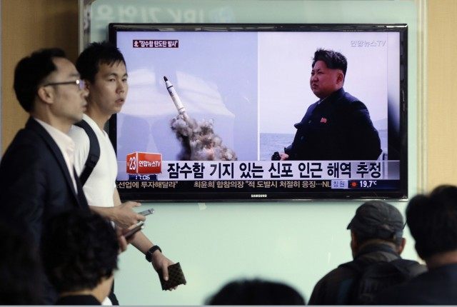 South Korean men pass by a TV news program showing images published in North Korea's Rodong Sinmun newspaper of North Korea's ballistic missile believed to have been launched from underwater and North Korean leader Kim Jong-un, at Seoul Railway station in Seoul, South Korea, Saturday, May 9, 2015. North Korea said Saturday it has successfully test-fired a newly developed ballistic missile from a submarine in what would be the latest display of the country's advancing military capability. The letters on the screen read "The missile believed to have been launched from underwater near Sinpo". (AP Photo/Ahn Young-oon)