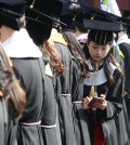 South Korean high school graduate Yoo Hye-jin checks her smartphone during a graduation ceremony at Sungkyunkwan University in Seoul, South Korea, Wednesday, Feb. 25, 2015. (AP Photo/Ahn Young-joon)
