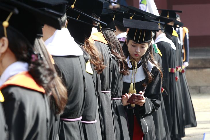 South Korean high school graduate Yoo Hye-jin checks her smartphone during a graduation ceremony at Sungkyunkwan University in Seoul, South Korea, Wednesday, Feb. 25, 2015. (AP Photo/Ahn Young-joon)