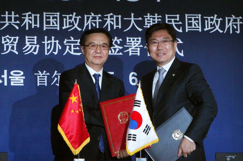 Chinese Commerce Minister Gao Hucheong, left, poses with his South Korean counterpart Yoon Sang-jick after signing documents for FTA or Free Trade Agreement during a signing ceremony in Seoul, South Korea Monday, June 1, 2015. South Korea and China signed a free trade deal that will remove tariffs on more than 90 percent of goods over two decades.The letters at back ground read "Free Trade Agreement signing ceremony between South Korea and China. (AP Photo/Ahn Young-joon)