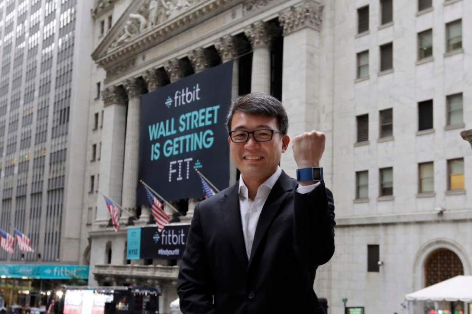 Fitbit CEO James Park shows off one of his devices as he poses for photos outside the New York Stock Exchange, before his company's IPO, Thursday, June 18, 2015. Fitbit makes devices that can be worn on the wrist or clipped to clothing to monitor daily steps, calories burned and grab other data. (AP Photo/Richard Drew)