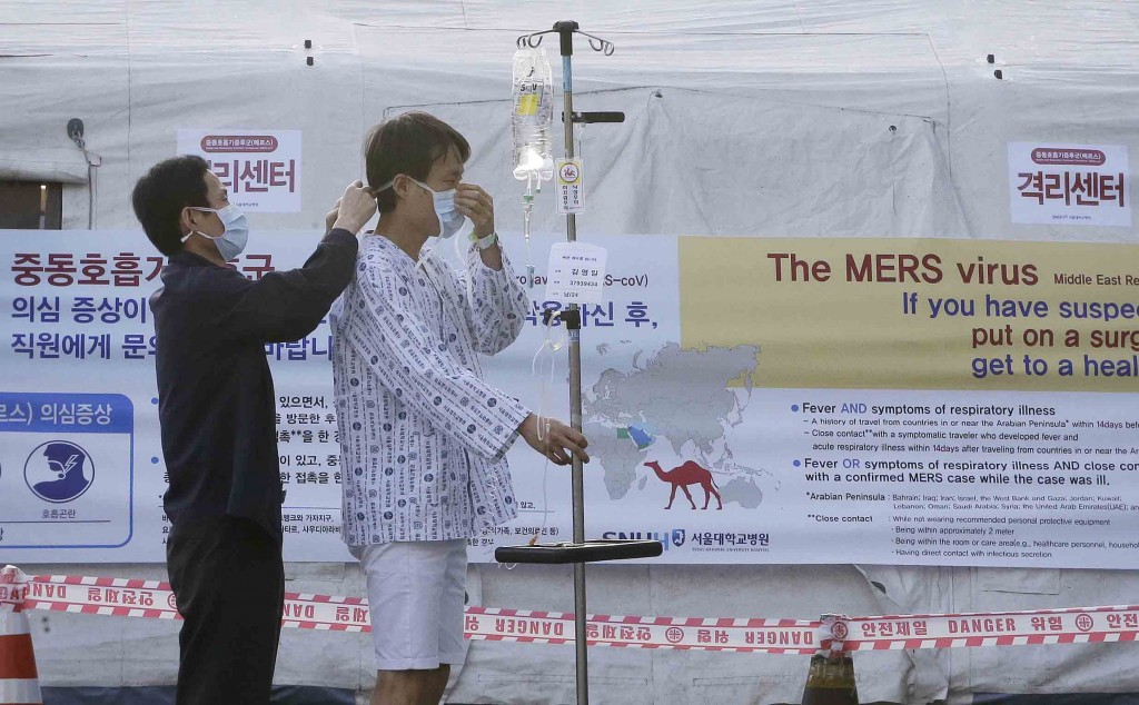 A man helps a patient to wear a mask as a precaution against the possible MERS, Middle East Respiratory Syndrome, virus in front of a facility to examine temporarily quarantined people who could be infected with the MERS virus at Seoul National University Hospital in Seoul, South Korea Monday, June 1, 2015. More than 680 people in South Korea are isolated after having contact with patients infected with the virus that has killed hundreds of people in the Middle East, health officials said Monday.(AP Photo/Ahn Young-joon)