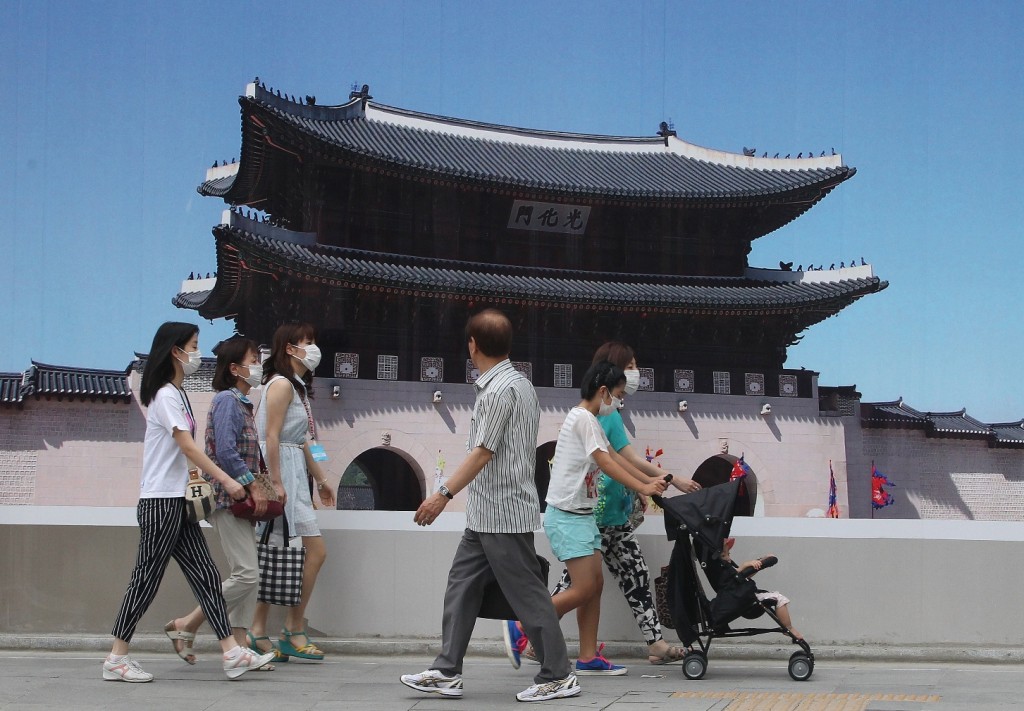 Women wearing masks as a precaution against the MERS (Middle East Respiratory Syndrome) pass by a picture of the Gwanghwamun, the main gate of the 14th-century Gyeongbok Palace and also one of South Korea's well known landmarks in Seoul, South Korea, Tuesday, June 30, 2015. South Korea's MERS outbreak originated from a 68-year-old man who had traveled to the Middle East, where the illness has been centered, before being diagnosed as the country's first MERS patient last month. (AP Photo/Ahn Young-joon)