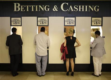 FILE - In this June 8, 2013, file photo, people stand at a betting and cashing window at Belmont Park in Elmont, N.Y., before the Belmont Stakes horse race. A $2 ticket on American Pharoah to win the Belmont Stakes may be worth a lot more money later than now. Or, people are hanging on to their own little piece of horse racing history. Two days after American Pharoah became the first Triple Crown winner in 37 years, more than 95 per cent of those who spent two bucks on a win ticket have yet to cash them. And for those still considering what to do, your deadline is March 31, 2016, or the money is returned to the state. (AP Photo/Seth Wenig, File)