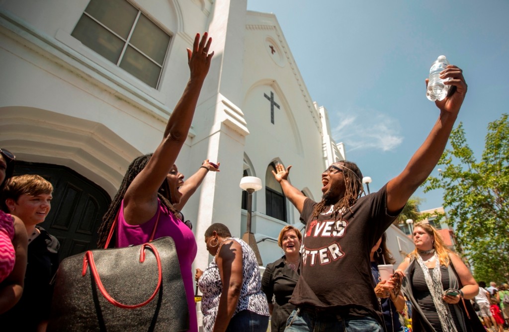 Rev. Jacqueline J. Lewis, left, of the Middle Collegiate Church in New York City and Muhiyidin D'Baha, right, of Black Lives Matter Charleston leads those in attendance in a song at the memorial in front of the Emanuel AME Church, Friday, June 19, 2015 in Charleston, S.C. (AP Photo/Stephen B. Morton)