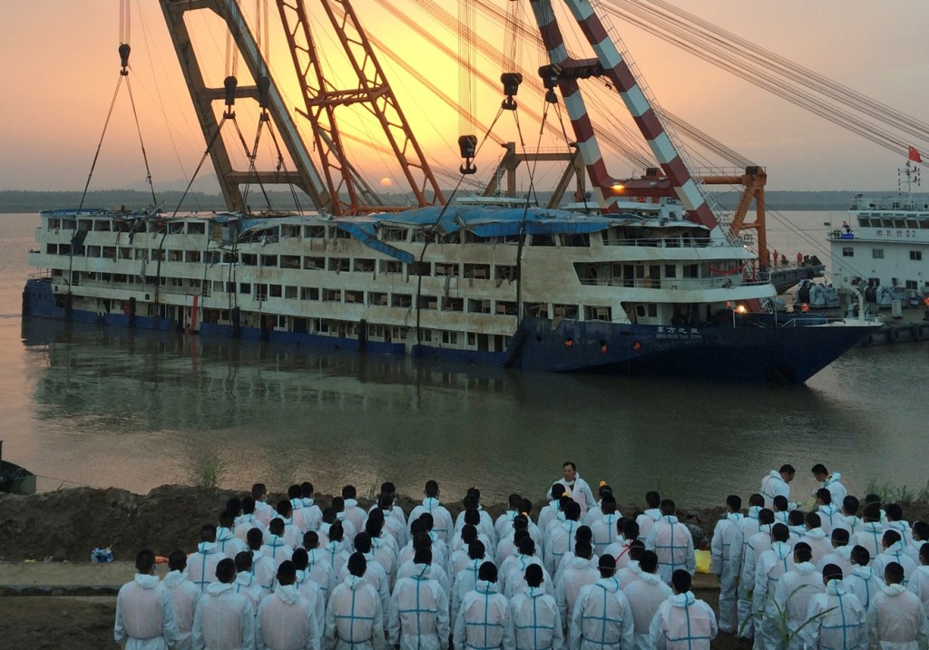 Paramilitary policemen in white overalls wait to recover bodies from the Eastern Star after it is righted and lifted by cranes in the Yangtze River in Jianli county in southern China's Hubei province Friday June 5, 2015. The smashed up white-and-blue Eastern Star emerged from gray waters of the Yangtze River on Friday as Chinese disaster teams raised the capsized ship with cranes to better search for hundreds still missing. (Chinatopix Via AP)