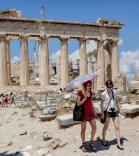 Tourists walk trough the ancient Acropolis hill, with the ruins of the fifth century BC Parthenon temple on the background in Athens, Monday, June 29, 2015. Anxious Greeks lined up at ATMs as they gradually began dispensing cash again on the first day of capital controls imposed in a dramatic twist in Greece's five-year financial saga. Banks will remain shut until next Monday, and a daily limit of 60 euros ($67) has been placed on cash withdrawals from ATMs. (AP Photo/Daniel Ochoa de Olza)