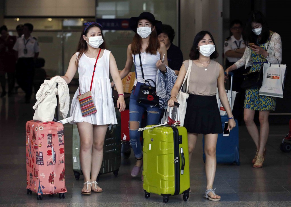 Passengers flying from Seoul, South Korea, wear masks as a precaution against MERS, Middle East Respiratory Syndrome, as they arrive at Hong Kong Airport Tuesday, June 9, 2015.  The Hong Kong government on Tuesday issued a red travel alert for South Korea because of the current MERS outbreak in the country. (AP Photo/Kin Cheung)