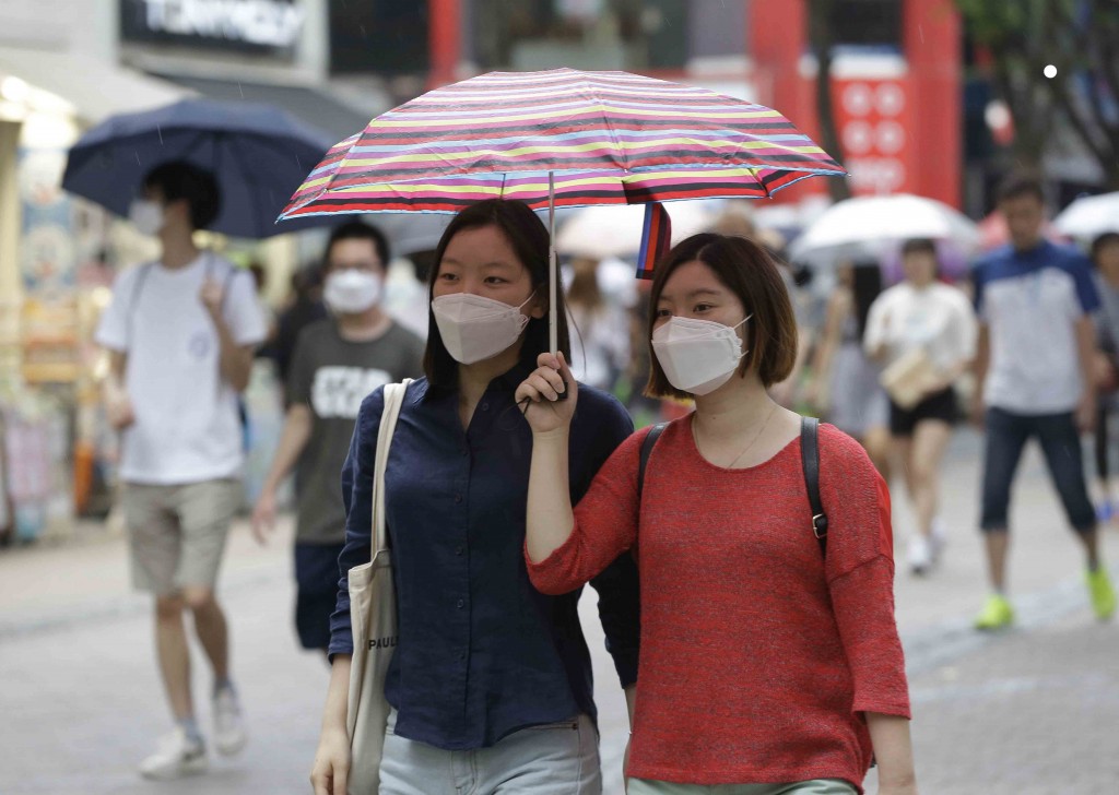 Women wear masks as a precaution against the Middle East Respiratory Syndrome virus as they walk on the Myeongdong, one of the main shopping districts, one of the main shopping districts in Seoul, South Korea Wednesday, June 17, 2015. The death toll continued to mount in South Korea's MERS outbreak on Tuesday even as schools reopen and people recover from the virus. (AP Photo/Ahn Young-joon)