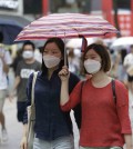 Women wear masks as a precaution against the Middle East Respiratory Syndrome virus as they walk on the Myeongdong, one of the main shopping districts, one of the main shopping districts in Seoul, South Korea Wednesday, June 17, 2015. The death toll continued to mount in South Korea's MERS outbreak on Tuesday even as schools reopen and people recover from the virus. (AP Photo/Ahn Young-joon)