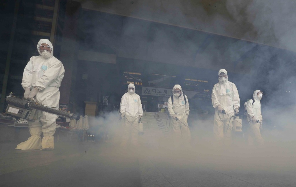 A worker wearing protective gear fumigates as a precaution against the spread of MERS, Middle East Respiratory Syndrome, virus outside Wangsimni Subway Station in Seoul, South Korea, Thursday, June 11, 2015. Experts from the World Health Organization and South Korea on Wednesday urged the reopening of more than 2,700 schools closed over fears of the deadly MERS virus.(AP Photo/Ahn Young-joon)