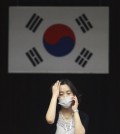 In this Thursday, June 18, 2015, file photo, an official wearing a mask as a precaution against the MERS virus works with a South Korean national flag in the background at Dongdaemun District Office in Seoul, South Korea. The head of the World Health Organization on Thursday praised beleaguered South Korean officials and exhausted health workers, saying their efforts to contain a deadly MERS virus outbreak have put the country on good footing and lowered the public risk. (AP Photo/Ahn Young-joon)