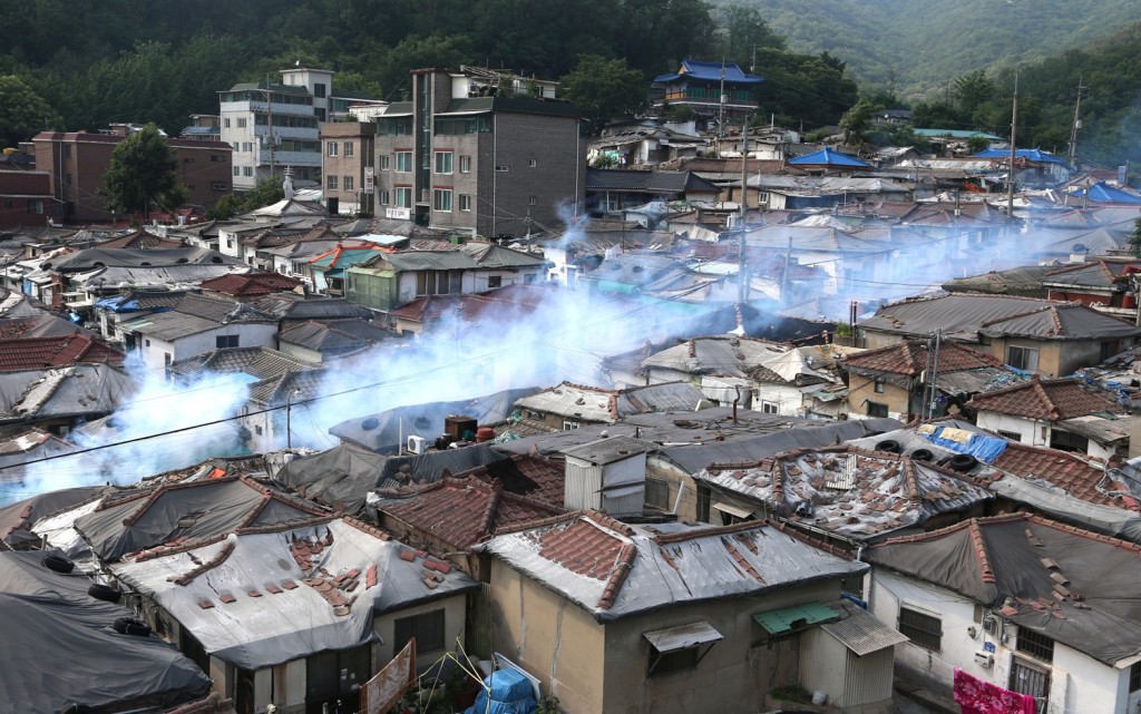 Smoke rises as disinfectant is sprayed as a precaution against the spread of Middle East Respiratory Syndrome (MERS) at a village in Seoul, South Korea, Friday, June 12, 2015. Authorities in South Korea temporarily closed two hospitals amid persistent fears over the MERS virus outbreak, which killed an 11th person Friday, though health officials said they are seeing fewer new infections. (Seo Myeong-gon/Yonhap via AP)