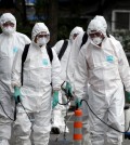 Workers wearing protective gears arrive to spray antiseptic solution as a precaution against the spread of Middle East Respiratory Syndrome (MERS) at an art hall in Seoul, South Korea, Friday, June 12, 2015. (AP Photo/Lee Jin-man)