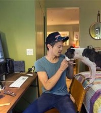 In this May 26, 2015, photo, freelance web designer Henry Brown pauses from his work at his New York apartment to give his dog Yogi a snack. Brown ditched his fledging advertising career 11 years ago, sick of spending 15 hours a day at work and having no time for himself. (AP Photo/Mark Lennihan)