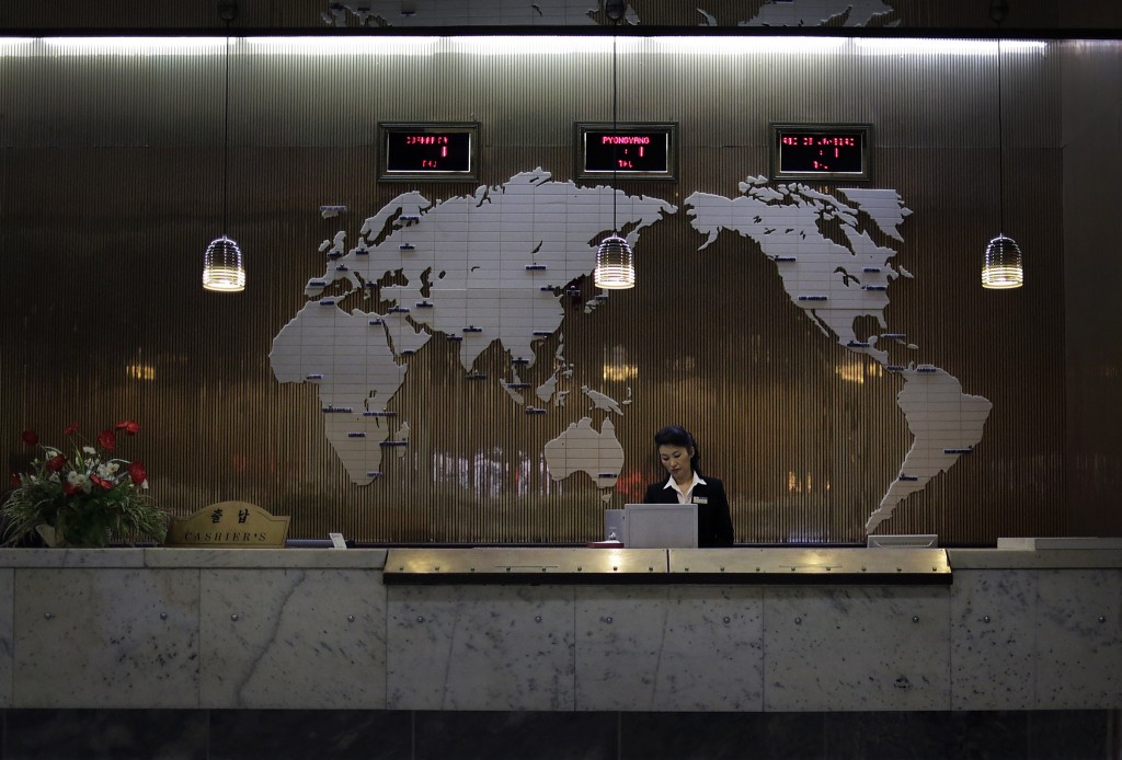 In this Thursday, Oct. 23, 2014, file photo, a hotel staff member stands at a reception desk of a hotel, decorated with a map of the world on the wall, in Pyongyang, North Korea. Fresh off a drastic, half-year ban that closed North Korea’s doors to virtually all foreigners over fears they would spread the Ebola virus - despite the fact that there were no cases of Ebola reported anywhere in Asia - the country is once again determined to show off its "socialist fairyland" to tourists. (AP Photo/Wong Maye-E, File)